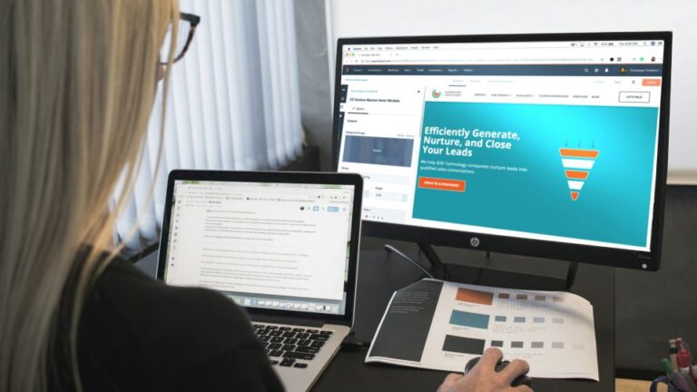 Woman working on website structure on two screens and paper