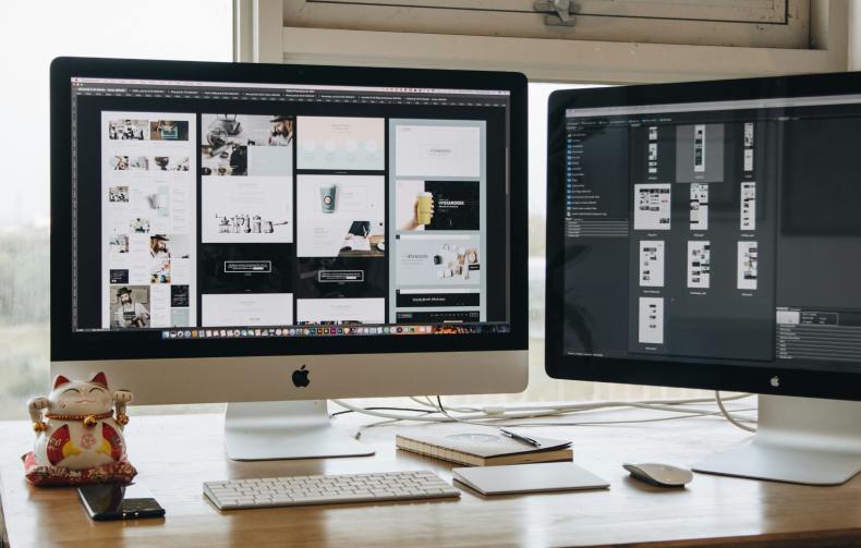 Two monitors with website design elements being refined