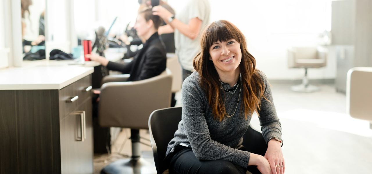 Hair salon owner sitting down, looking content with her business