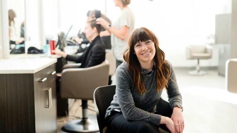 Hair salon owner sitting down, looking content with her business