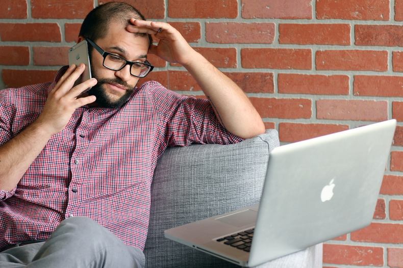A frustrated business owner on the phone looking at a laptop