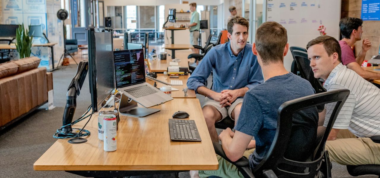 Three business owners sitting by a desktop computer having a discussion