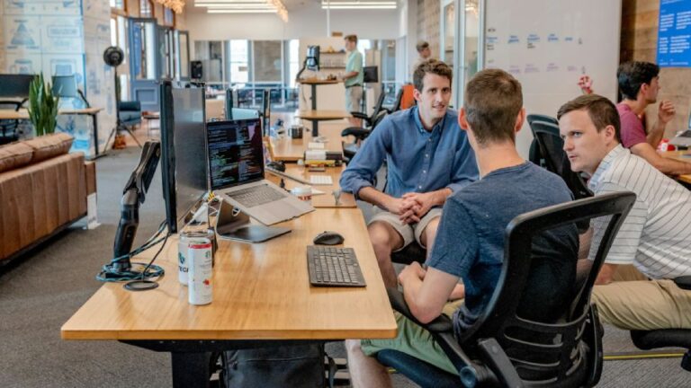 Three business owners sitting by a desktop computer having a discussion